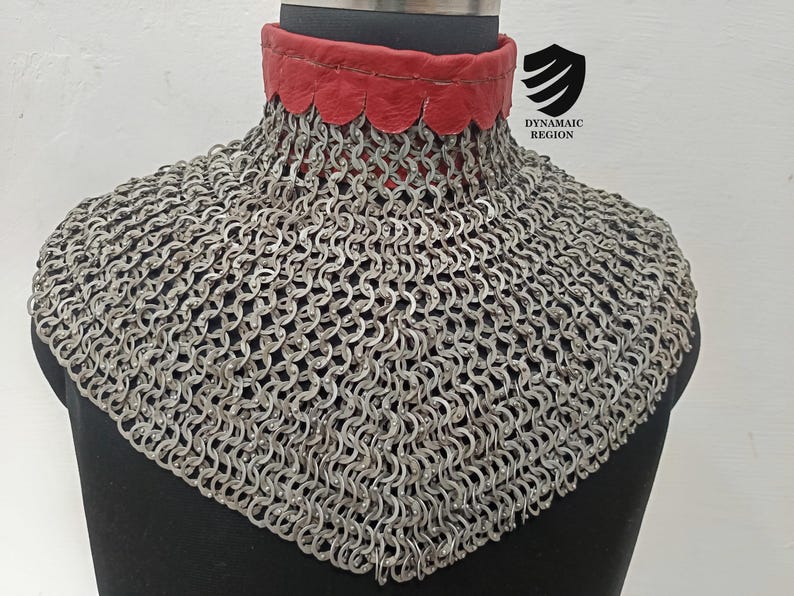 May include: A silver chainmail collar with a red leather lining. The collar is on a mannequin and has a scalloped edge.