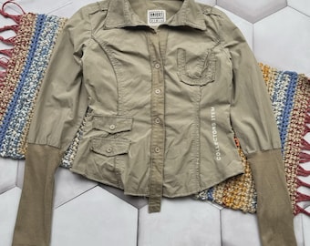 May include: A tan button-up shirt with long sleeves and multiple pockets. The shirt has a collared neckline and the text "COLLECTORS ITEM" is printed vertically on the right side. The brand logo "OBJECT" is visible on the upper chest.