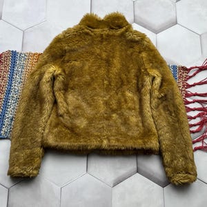 May include: A mustard yellow faux fur jacket with a high collar and long sleeves.