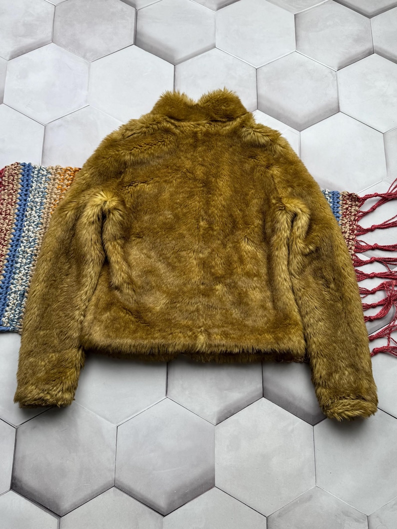 May include: A mustard yellow faux fur jacket with a high collar and long sleeves.