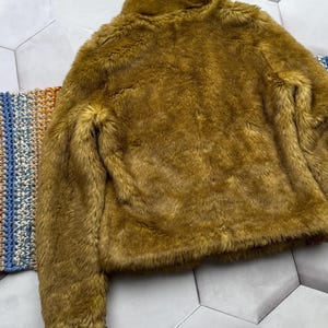 May include: A brown faux fur jacket with a high collar and long sleeves.