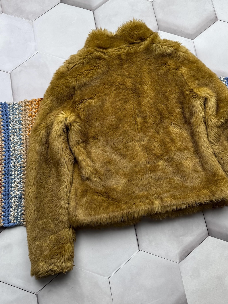 May include: A brown faux fur jacket with a high collar and long sleeves.