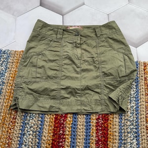 May include: A green cargo skirt with multiple pockets and a button fastening.