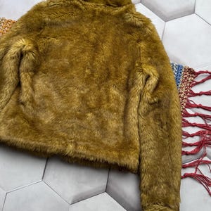 May include: A soft, plush, mustard yellow faux fur jacket with a high collar and long sleeves.