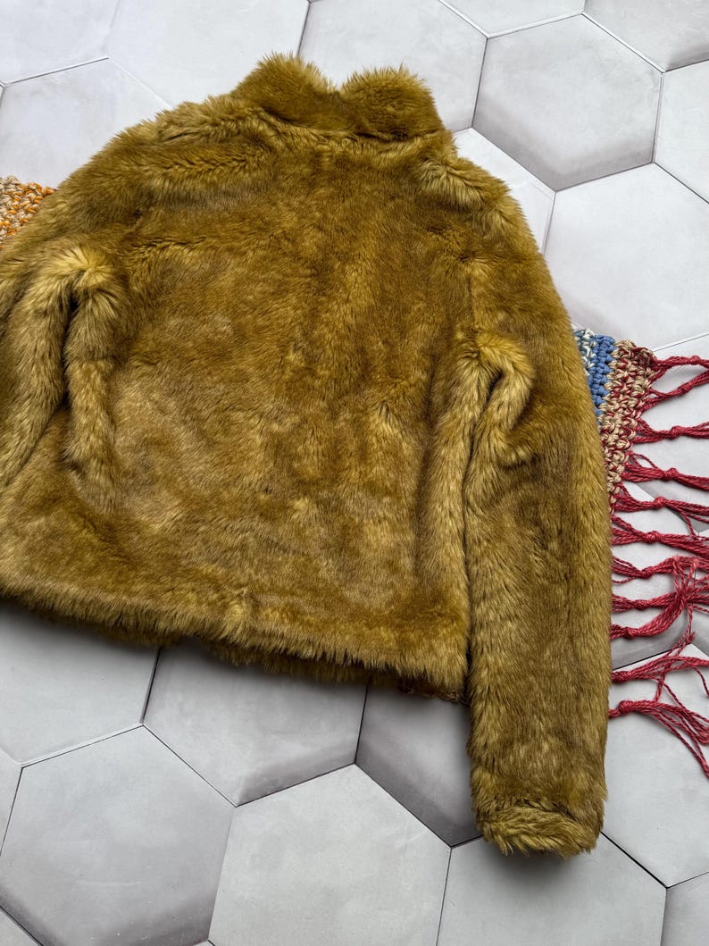 May include: A soft, plush, mustard yellow faux fur jacket with a high collar and long sleeves.