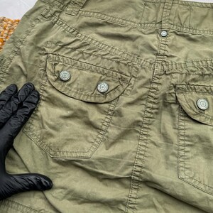 May include: A green cargo skirt with two large pockets and button closures. The skirt is made of a lightweight, durable fabric.