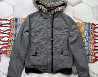 May include: Gray hooded jacket with a faux fur trim around the hood. The jacket has a zipper closure and button accents. The jacket has two pockets on the front.
