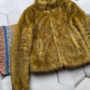 May include: A brown faux fur jacket with a high collar and a zipper closure.