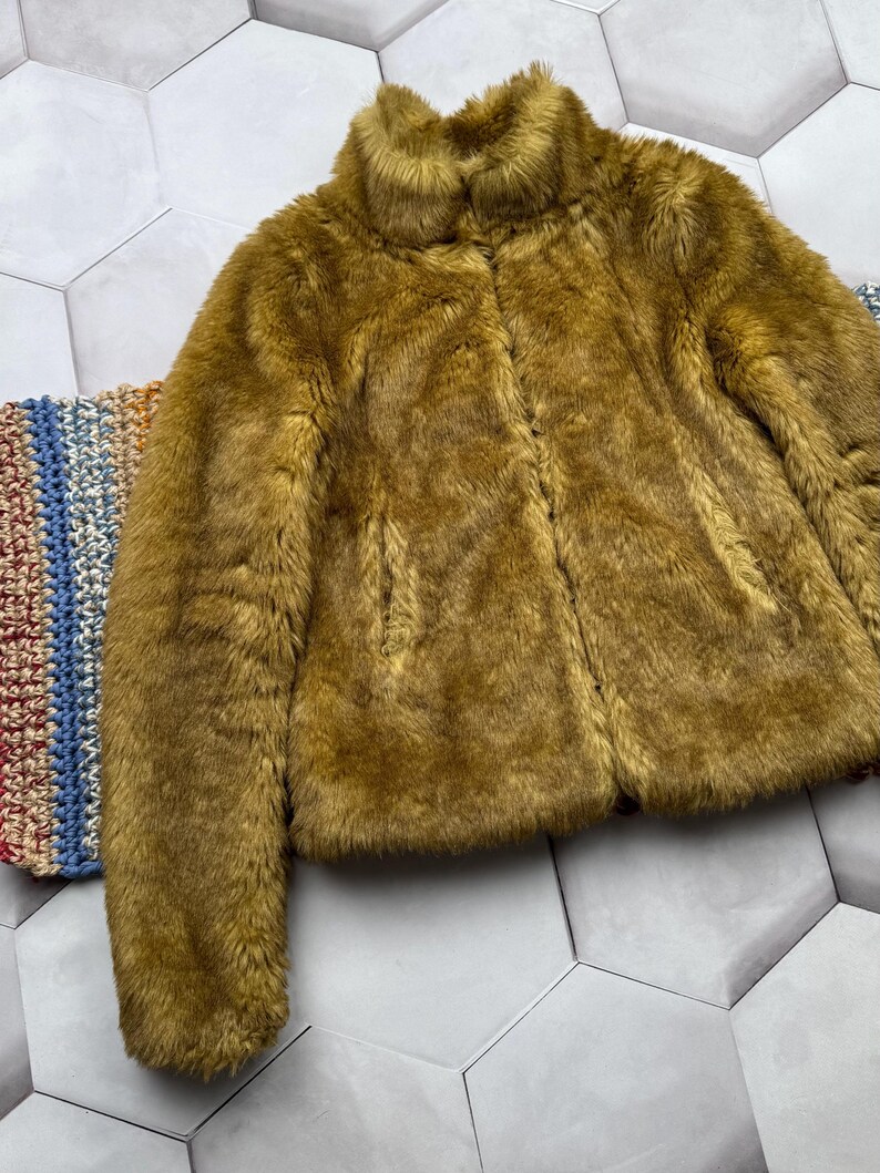 May include: A brown faux fur jacket with a high collar and a zipper closure.