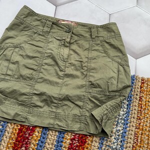 May include: A green cargo skirt with multiple pockets and a button fastening. The skirt is made from a lightweight fabric and has a relaxed fit.