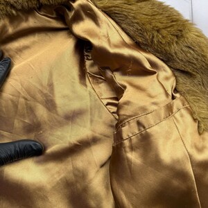 May include: A brown faux fur collar with a gold satin lining. The collar is soft and fluffy, and the lining is smooth and silky.
