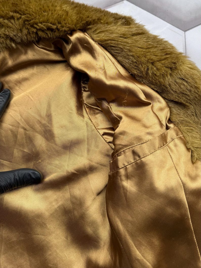 May include: A brown faux fur collar with a gold satin lining. The collar is soft and fluffy, and the lining is smooth and silky.