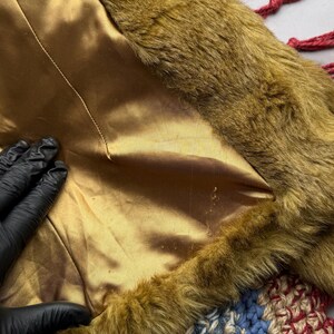 May include: Close-up of a brown faux fur trim with a gold satin lining. The fur is soft and fluffy, and the lining is smooth and silky.