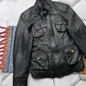 May include: A black leather jacket with a zipper closure and multiple pockets. The jacket has a stand-up collar and a quilted lining.