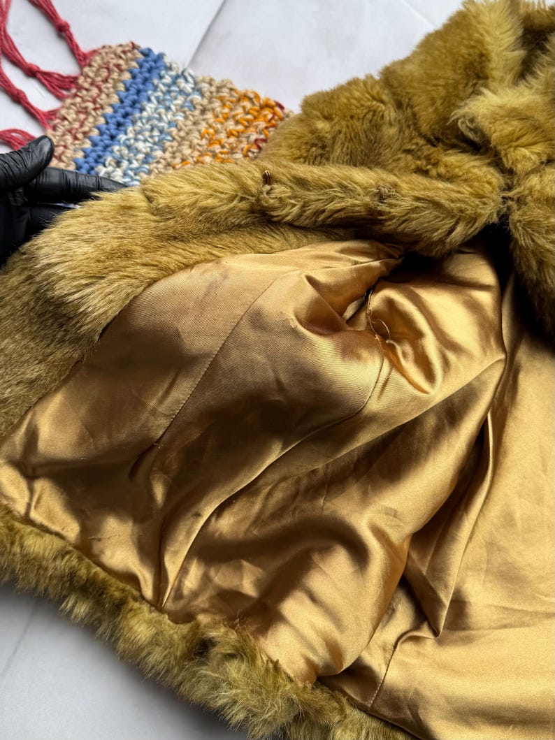 May include: A mustard yellow faux fur jacket with a gold satin lining. The jacket is unbuttoned and the lining is visible.