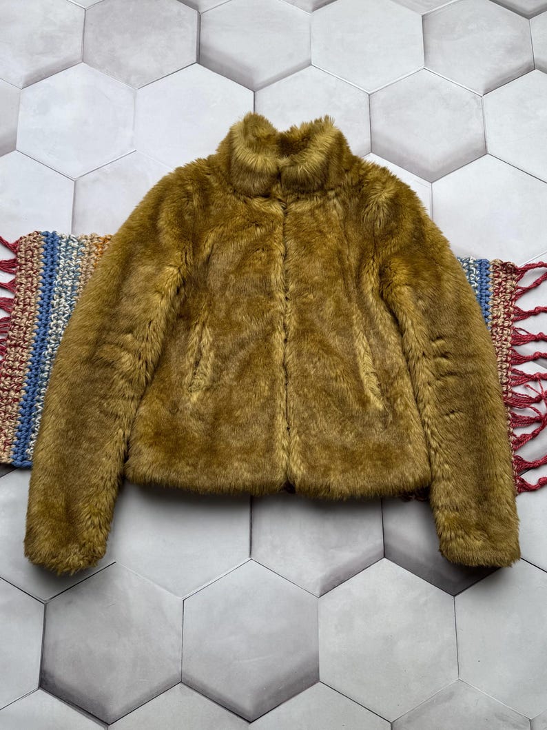 May include: A brown faux fur jacket with a high collar and zipper closure.