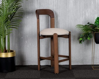 Könnte beinhalten: Ein Barhocker aus Holz mit einem hellbraunen gepolsterten Sitz. Der Hocker hat einen dunkelbraunen Holzrahmen und ein schlichtes Design.