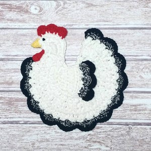 May include: White crocheted chicken kitchen dishcloth with black and red accents.