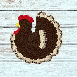 May include: A brown crocheted turkey with a red and yellow head and a tan and brown tail.