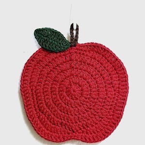 May include: A red crocheted apple with a green crocheted leaf. The apple is a handmade kitchen decor item.