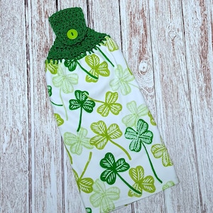 May include: A green crocheted dish towel with a button and a shamrock pattern.