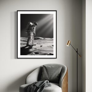 May include: Black and white photograph of an astronaut playing golf on the moon. The astronaut is wearing a spacesuit and carrying a golf club. Sunlight beams down on the astronaut. The photo is displayed in a black frame on a wall above a gray armchair with a brown leather side. A gold floor lamp is in the corner of the room.
