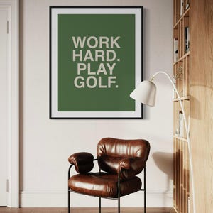 K&ouml;nnte beinhalten: Ein gerahmter Druck mit gr&uuml;nem Hintergrund und wei&szlig;em Text, der "WORK HARD. PLAY GOLF." lautet.