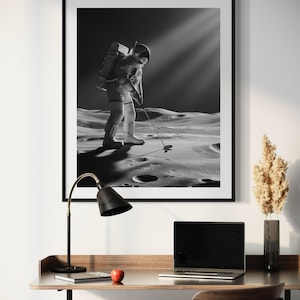 K&ouml;nnte beinhalten: Ein Schwarzwei&szlig;foto eines Astronauten, der auf dem Mond Golf spielt. Der Astronaut tr&auml;gt einen Raumanzug und h&auml;lt einen Golfschl&auml;ger in der Hand. Die Mondoberfl&auml;che ist im Hintergrund zu sehen.