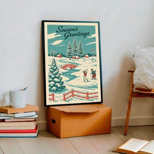 May include: A framed print depicting a winter golf scene. The artwork shows a snowy landscape with a bridge, trees, and golfers. The words "Season's Greetings" are at the top. The print is in a black frame and is displayed on a brown box.