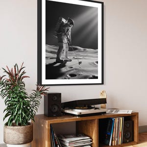 K&ouml;nnte beinhalten: Ein Schwarzwei&szlig;foto eines Astronauten, der auf dem Mond Golf spielt. Der Astronaut tr&auml;gt einen Raumanzug und h&auml;lt einen Golfschl&auml;ger in der Hand. Die Mondoberfl&auml;che ist im Hintergrund zu sehen.