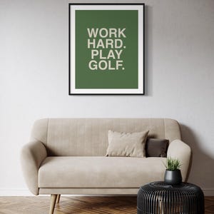 K&ouml;nnte beinhalten: Ein gerahmter Druck mit gr&uuml;nem Hintergrund und wei&szlig;em Text, der "WORK HARD. PLAY GOLF." lautet.