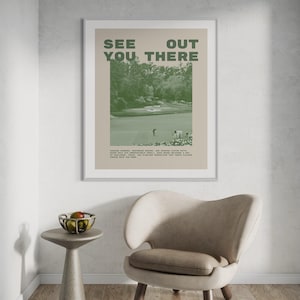 a framed poster with the text "See You There" displayed on a wall above a beige armchair in a room.