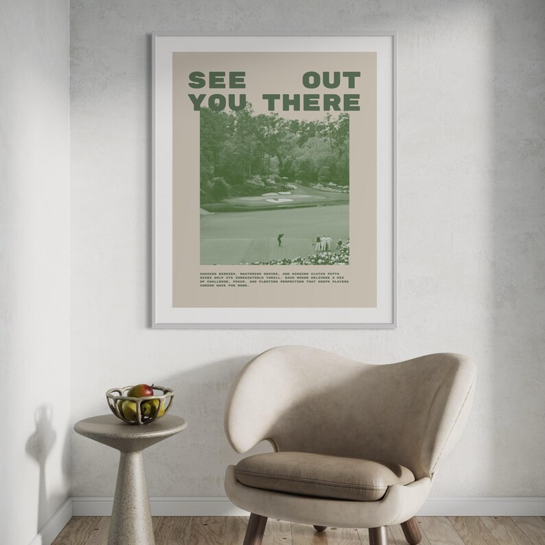 a framed poster with the text "See You There" displayed on a wall above a beige armchair in a room.