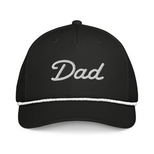 Op de afbeelding: Zwarte baseballcap met het woord "Dad" in witte letters op de voorkant geborduurd. De cap heeft een wit touwdetail langs de rand en een gebogen klep. Een stijlvol en comfortabel accessoire.