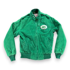 May include: A bright green corduroy jacket featuring a stand-up collar with a snap button closure, a full-length front zipper, and ribbed cuffs and hem. An oval patch with the text CCS is stitched onto the left chest area of the garment.