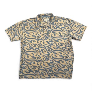 May include: A short-sleeve polo shirt featuring a tan and blue swirling wave pattern. The shirt has a collared neckline with a two-button placket and a small interior tag that reads "Tommy Bahama" with the size XL clearly visible below the text.