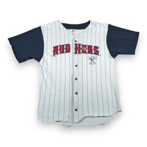 May include: White baseball jersey with navy blue sleeves and pinstripes. The jersey features the words "Mud Hens" in red block letters across the chest, with a cartoon logo below. The jersey has a button-up front.