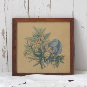 Peut inclure: Une impression botanique encadrée représentant une illustration détaillée d'une composition florale. L'œuvre présente un bouquet aux teintes bleues, jaunes et vertes, sur un fond beige. L'impression est encadrée dans un cadre en bois brun foncé.