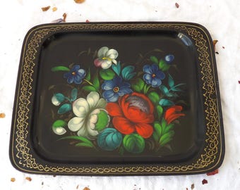 May include: A black metal tray with a gold border and a hand-painted floral design featuring red, white, blue, and green flowers.