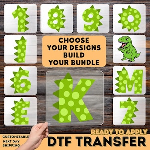 May include: A collection of DTF (Direct to Film) transfer designs featuring dinosaur-themed numbers and letters in green with white polka dots. The image includes a cartoon dinosaur and text that reads "CHOOSE YOUR DESIGNS BUILD YOUR BUNDLE".