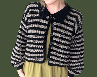 May include: A black and beige striped crocheted cardigan with a collared neckline and button closure.