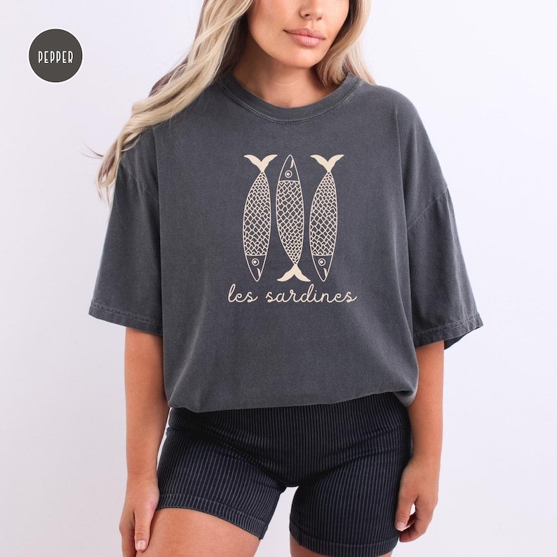 Op de afbeelding: Een donkergrijs gecropped t-shirt met een afbeelding van drie sardines en de tekst "les sardines" in een lichte cr&egrave;mekleur.