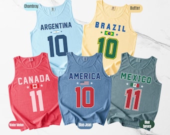May include: Five sleeveless tank tops in various colors, each featuring a country's name and flag, along with a number. The colors include light blue, yellow, red, blue, and gray. The tank tops are labeled Argentina, Brazil, Canada, America, and Mexico.