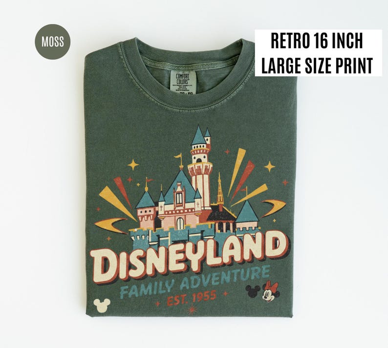 Puede incluir: Una camiseta verde musgo con un gr&aacute;fico retro de Disneyland. El dise&ntilde;o presenta un castillo, la palabra "Disneyland" y el texto "Family Adventure Est. 1955". La camiseta tiene una etiqueta "Retro 16 inch Large Size Print".