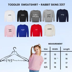 Puede incluir: Una selecci&oacute;n de sudaderas para ni&ntilde;os peque&ntilde;os en varios colores, incluyendo blanco, negro y azul marino. La imagen muestra el texto "TODDLER SWEATSHIRT - RABBIT SKINS 3317" y una tabla de tallas con medidas en cm.