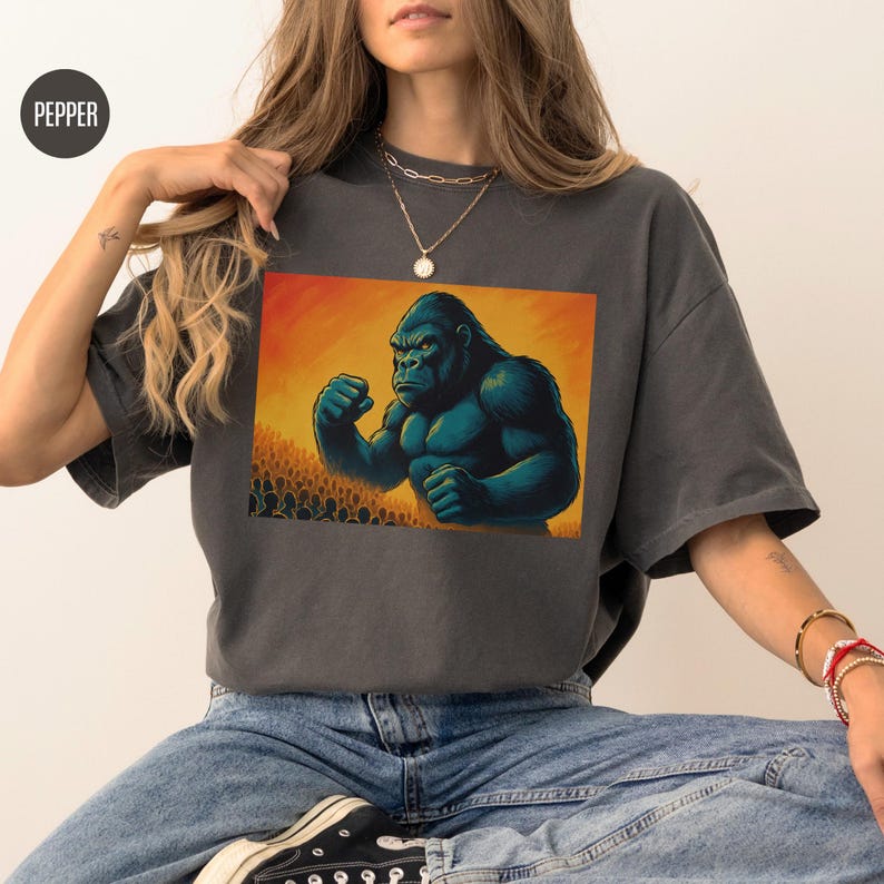 May include: A dark gray t-shirt with a graphic print of a large, muscular gorilla with a yellow background. The gorilla is in a fighting stance with its fists clenched.