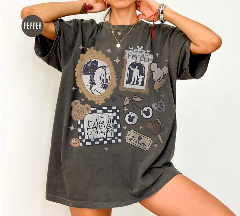 May include: Dark gray t-shirt featuring various cartoon graphics, including Mickey Mouse, cherries, and an ice cream bar. The shirt has a vintage, distressed look with the word "Dream" on a ticket.