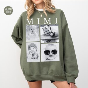 May include: Military green sweatshirt with the word "MIMI" in white block letters. The sweatshirt features four black and white photos of babies. One baby is wearing sunglasses. The sweatshirt is a casual style.