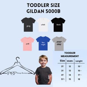 May include: A product image featuring a variety of toddler-sized Gildan 5000B t-shirts in various colors, including gray, white, black, pink, true royal, and sport gray. A size chart is included, with measurements in inches. The image also includes a child wearing a gray t-shirt.