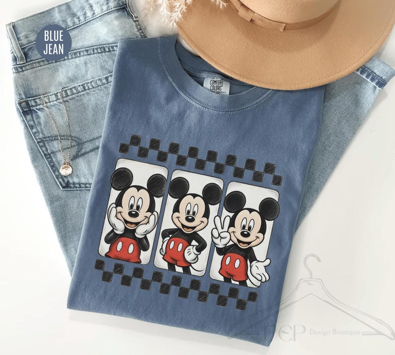 Puede incluir: Una camiseta azul con tres im&aacute;genes de Mickey Mouse en diferentes poses, cada una enmarcada por un patr&oacute;n de cuadros blancos y negros. La camiseta se muestra con vaqueros azules y un sombrero beige.